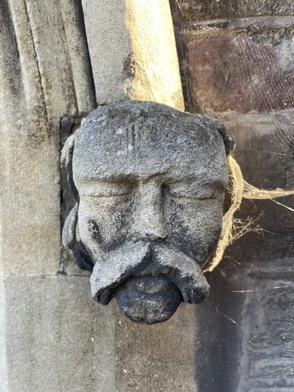 A carved man's face with closed eyes and pursed lips