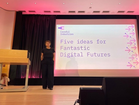 A white woman with a dark bob on stage with a slide 'Five ideas for Fantastic Digital Futures'