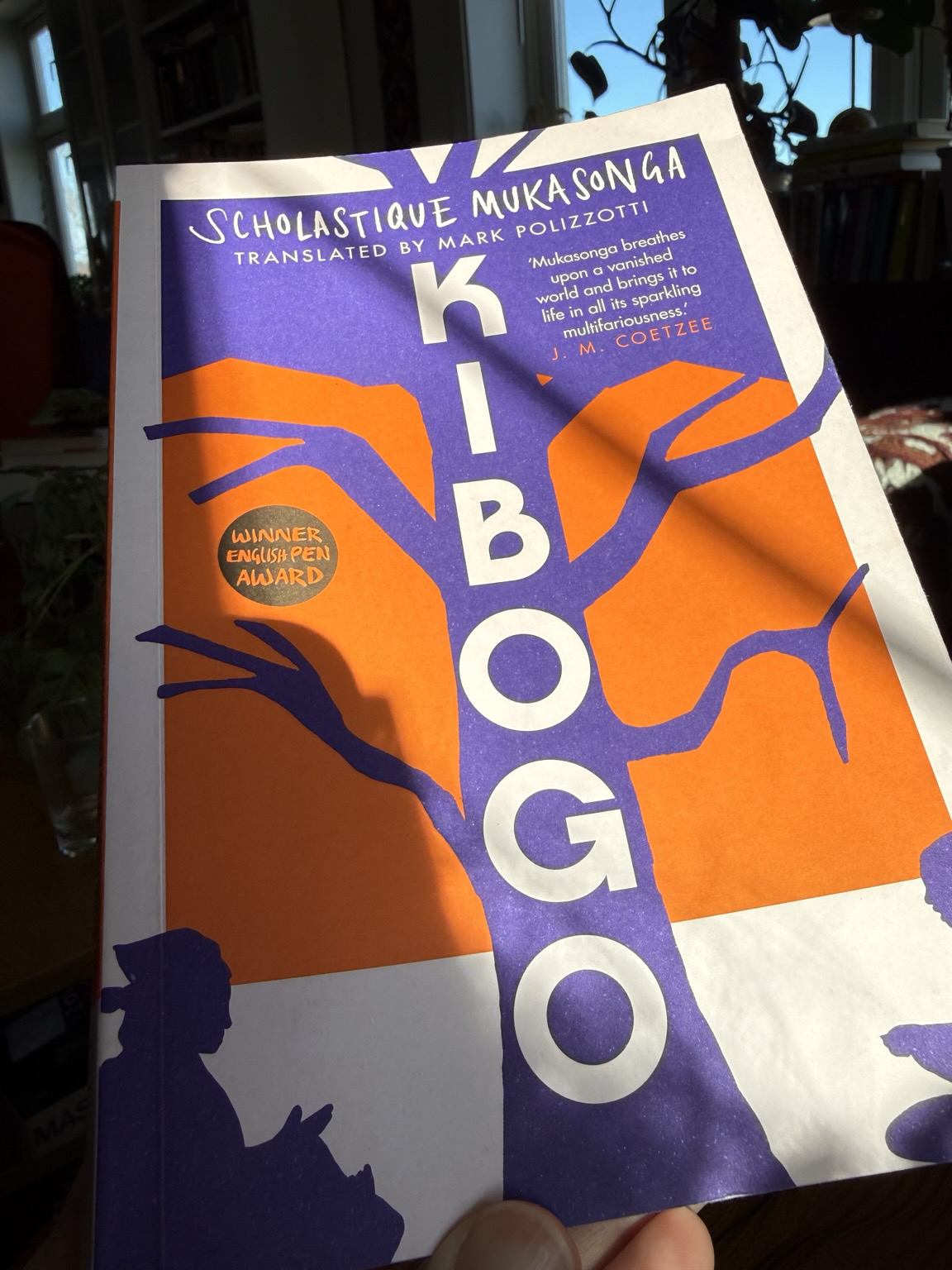 Cover of Kibogo. White background with a stylised purple tree against an orange sky. The title is in white against the tree trunk.