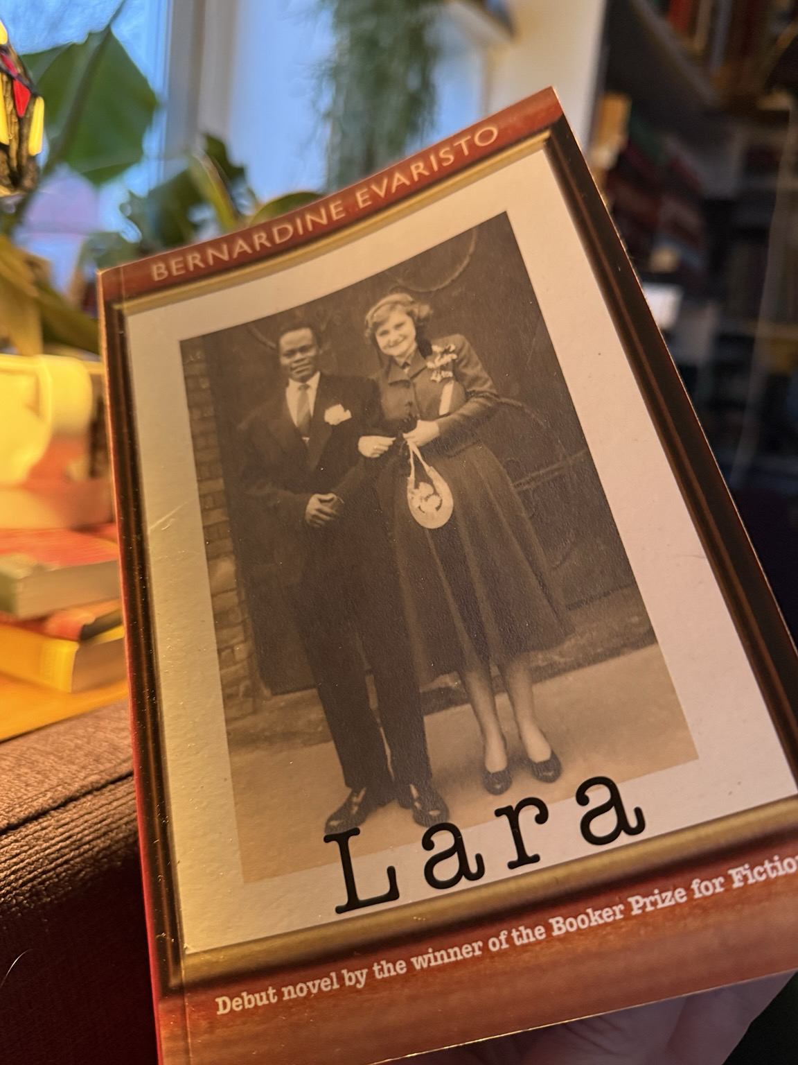 Cover of Lara. It is brown with a large framed photo of the author’s parents (a white woman and a black man) on their wedding day some time in the 1950s. The title is given in black and author name in white capitals. At the bottom of the cover it says “Debut novel by the winner of the Booker Prize for Fiction".