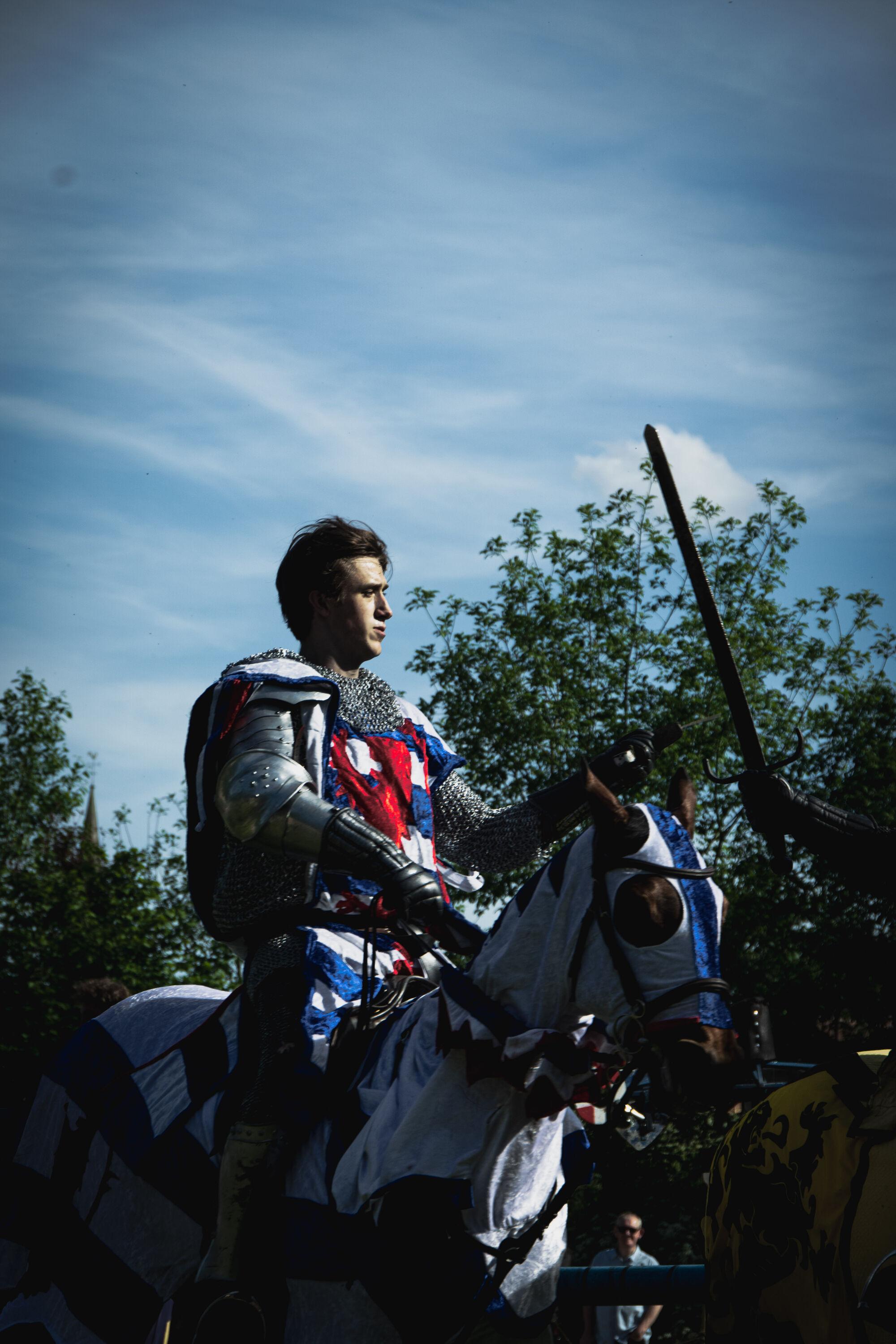 Male reenactor in medieval knight costume riding a a horse.