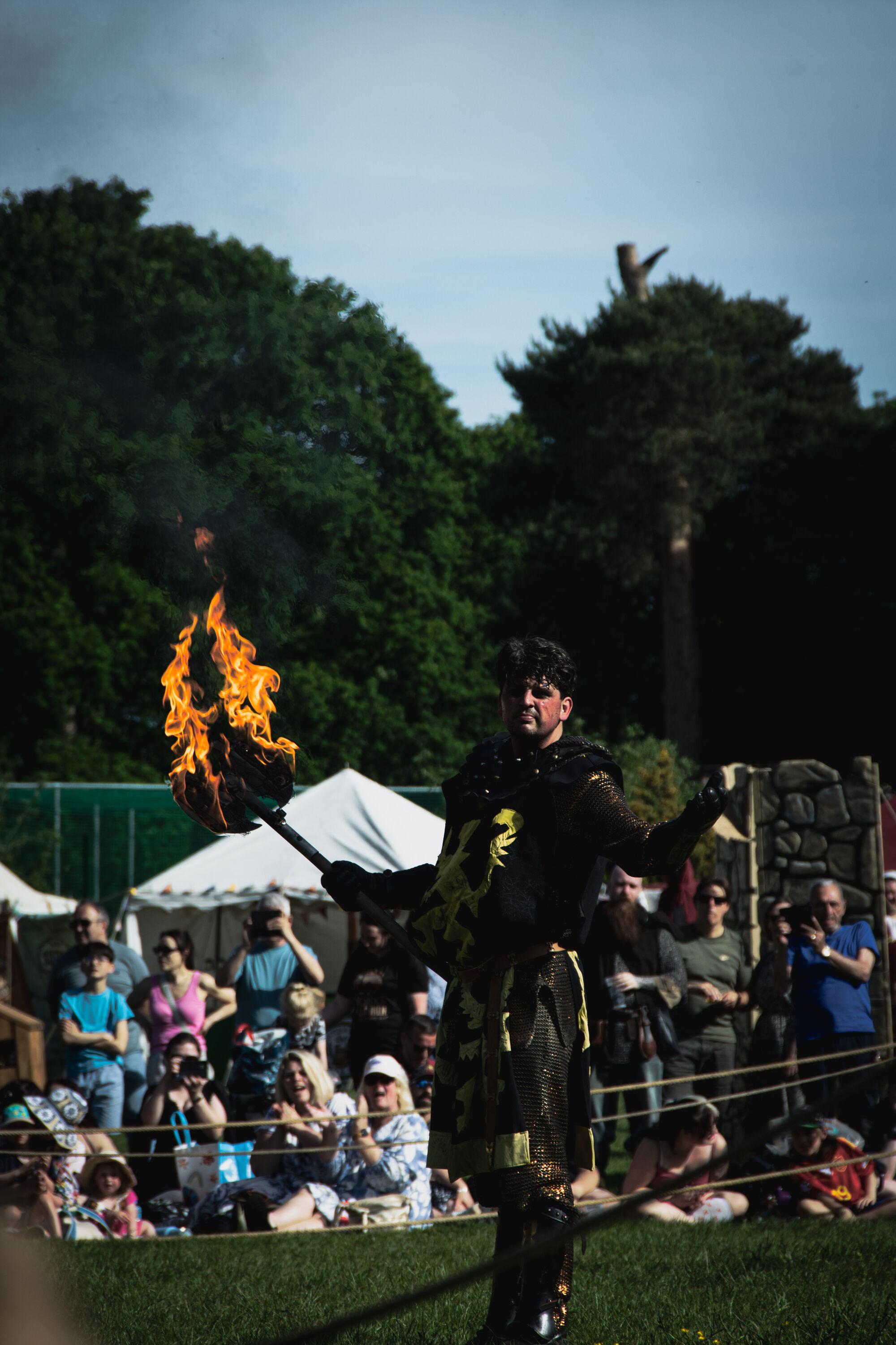 A reenactor dressed up as a 'black night' wielding a fire-lit axe.