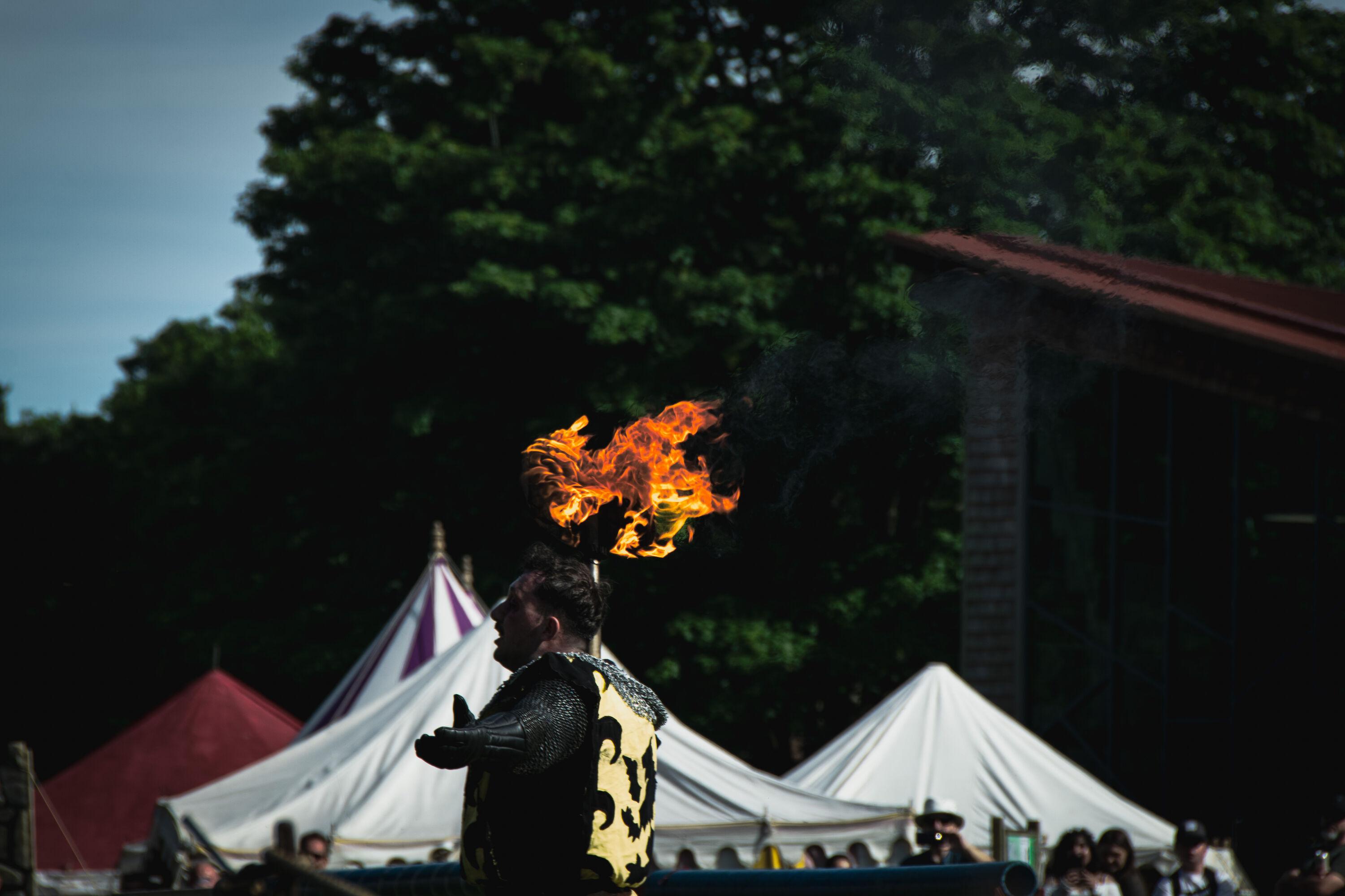 A reenactor dressed up as the 'black knight' wiedling a fire-lit axe.