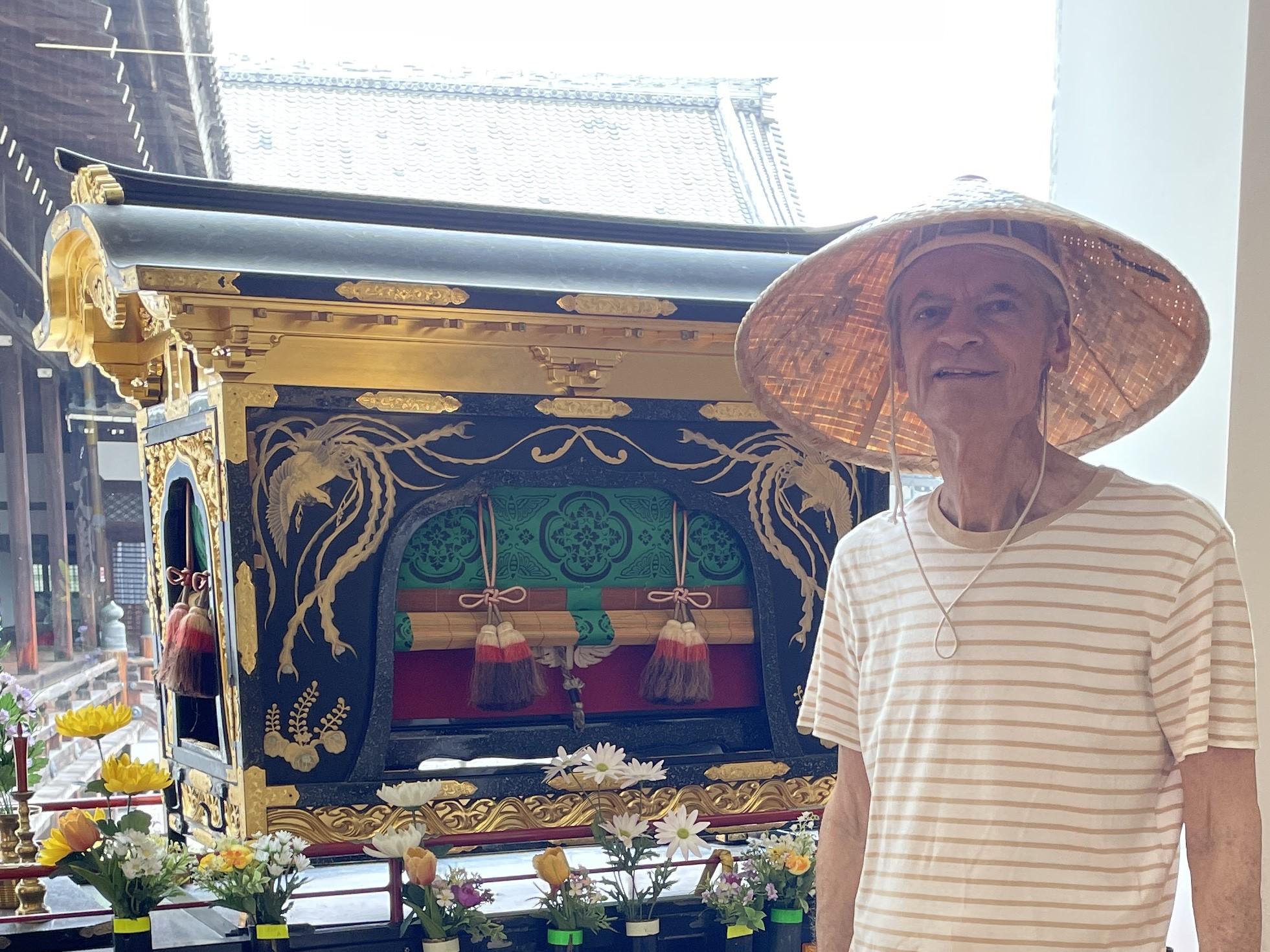 Cosplaying as a Buddhist pilgrim in front of a portable shrine for carrying Shintō gods