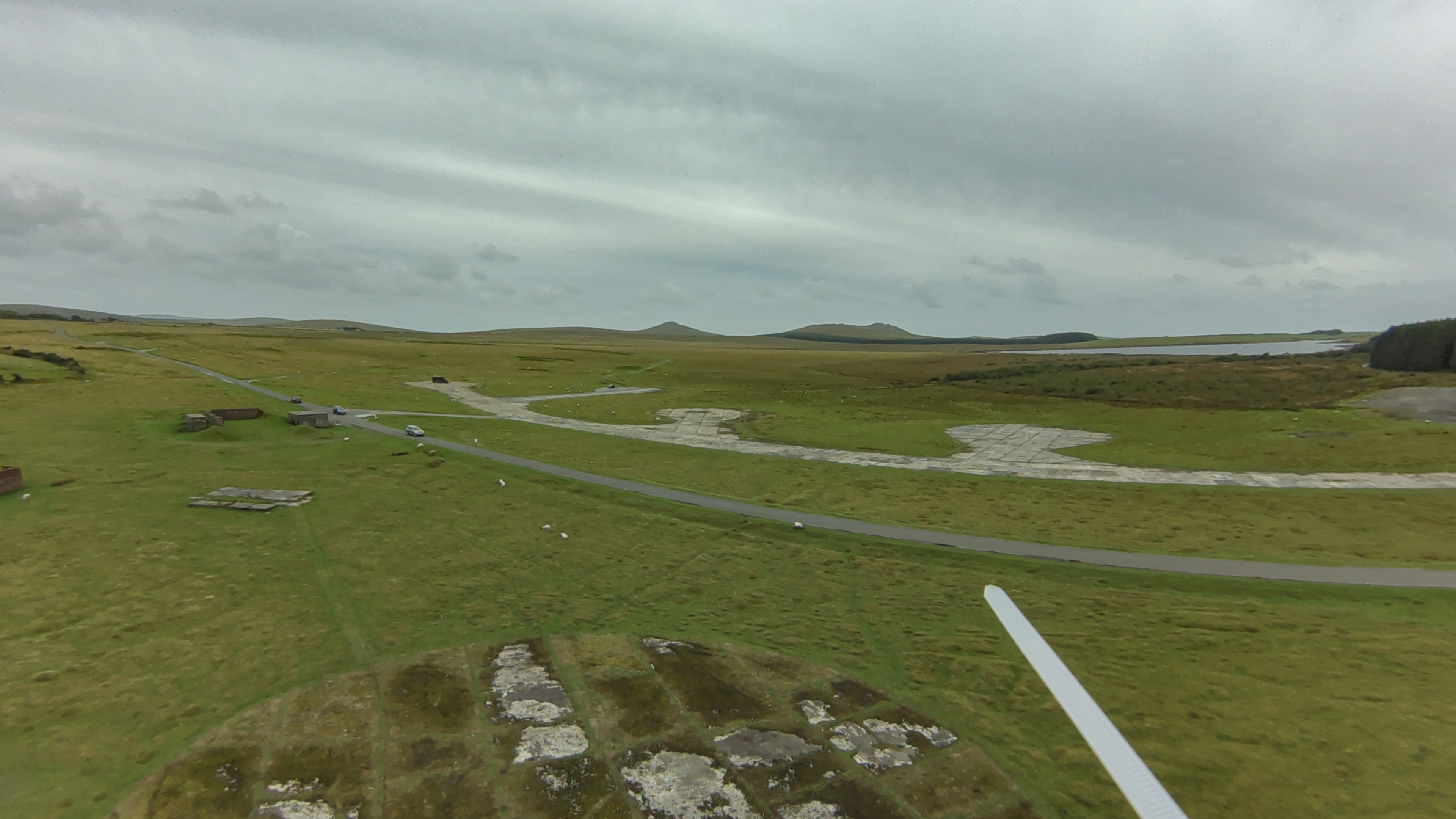 An aerial shot of Davidstoor moor. Expanse of grass, crumbling WW2 taxiways, and the giant tors of Rough Tor and Brown Willy in the far distance