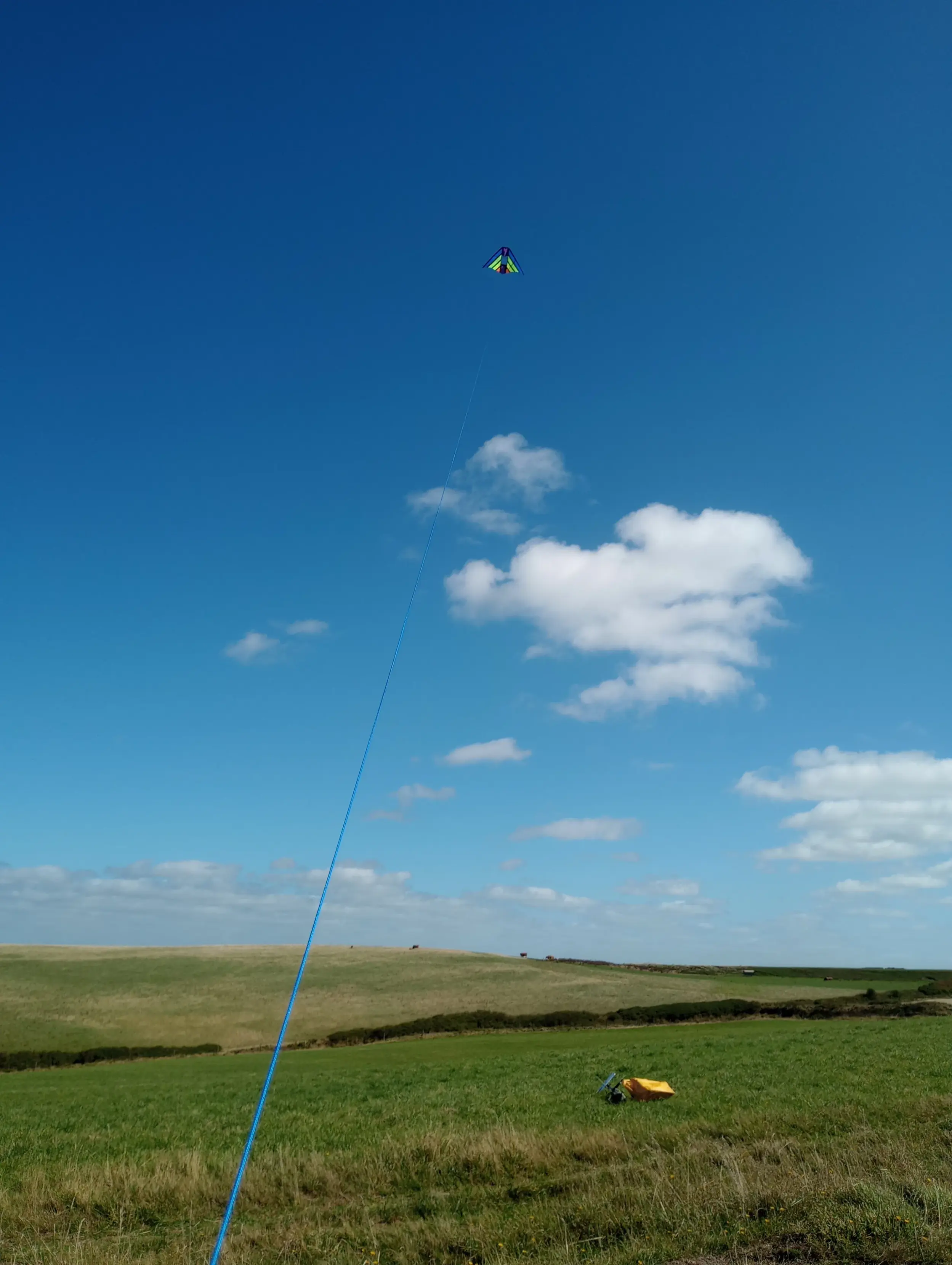 A colourful delta kite flies high over farmland